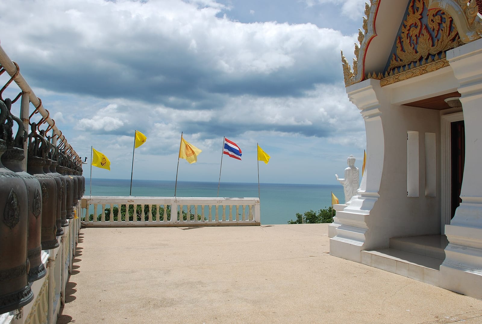 Clifftop terrace of Wat Tham Khao Tao with temple bells and sea view